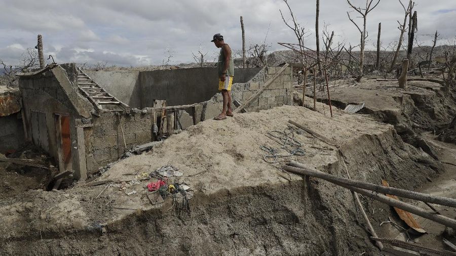 Fisherman Rogelito Cacao looks at the remains of his house at the Taal volcano almost a year after it erupted on Sunday, Jan. 10, 2021 in Batangas province, Philippines. Cacao regularly visits the area after feeding fish at the pens on the Taal lake. A popular tourist destination just south of Manila because of its picturesque setting in the middle of a lake, Taal erupted on Jan. 12, 2020. The eruption displaced thousands of villagers living near the area and delivered an early crisis this year for one of the world's most disaster-prone nations a couple of months before the COVID-19 pandemic broke in the country. (AP Photo/Aaron Favila)