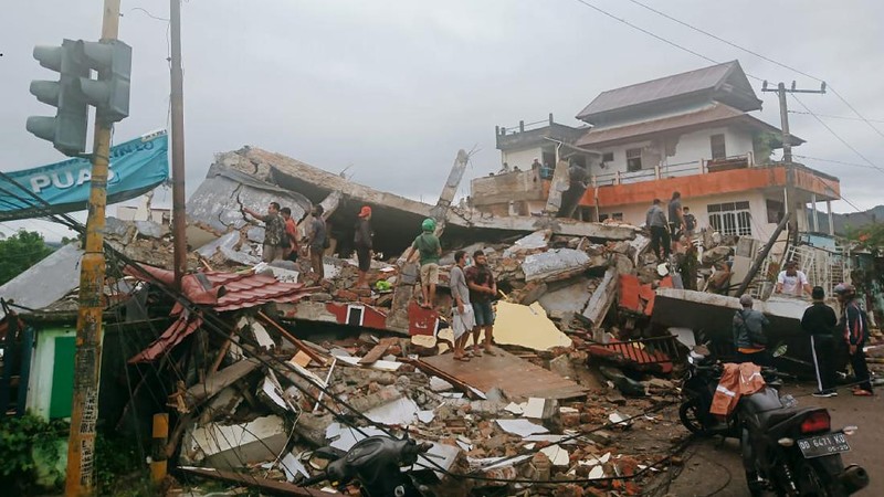 Recuers search for survivors among the ruin of a building damaged by an earthquake in Mamuju, West Sulawesi, Indonesia, Friday, Jan. 15, 2021. A strong, shallow earthquake shook Indonesia's Sulawesi island just after midnight, causing landslides and sending people fleeing from their homes in the nighttime darkness. (AP Photo/Sadly Ashari Said)