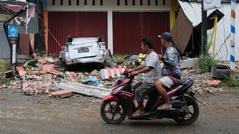 Recuers search for survivors among the ruin of a building damaged by an earthquake in Mamuju, West Sulawesi, Indonesia, Friday, Jan. 15, 2021. A strong, shallow earthquake shook Indonesia's Sulawesi island just after midnight, causing landslides and sending people fleeing from their homes in the nighttime darkness. (AP Photo/Sadly Ashari Said)