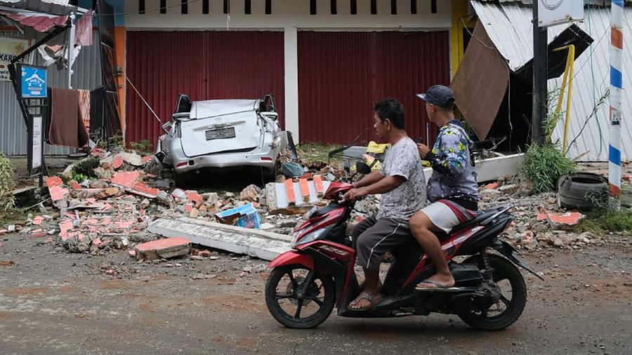 Recuers search for survivors among the ruin of a building damaged by an earthquake in Mamuju, West Sulawesi, Indonesia, Friday, Jan. 15, 2021. A strong, shallow earthquake shook Indonesia's Sulawesi island just after midnight, causing landslides and sending people fleeing from their homes in the nighttime darkness. (AP Photo/Sadly Ashari Said)