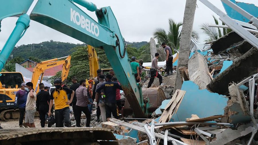 Recuers search for survivors among the ruin of a building damaged by an earthquake in Mamuju, West Sulawesi, Indonesia, Friday, Jan. 15, 2021. A strong, shallow earthquake shook Indonesia's Sulawesi island just after midnight, causing landslides and sending people fleeing from their homes in the nighttime darkness. (AP Photo/Sadly Ashari Said)