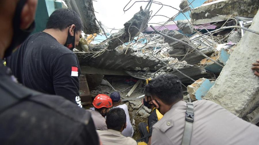 Rescuers search for survivors among the ruin of a building damaged by an earthquake in Mamuju, West Sulawesi, Indonesia, Friday, Jan. 15, 2021. A strong, shallow earthquake shook Indonesia's Sulawesi island just after midnight Friday, toppling homes and buildings, triggering landslides. (AP Photo/Daus Thobelulu)