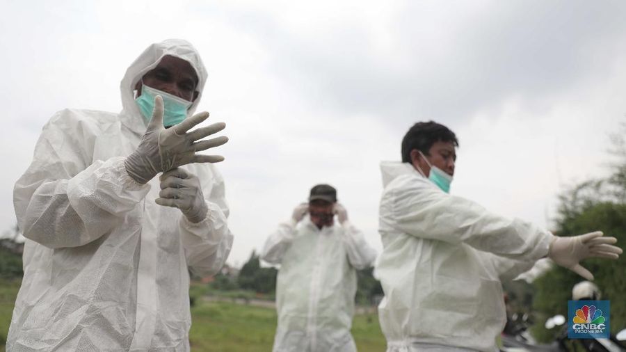 Petugas membawa peti jenazah yang akan dimakamkan dengan protokol COVID-19 di area khusus TPU Srengseng Sawah, Jakarta, Jumat (15/1/2021). TPU Srengseng Sawah mulai menerima pemakaman jenazah dengan protokol COVID-19 sejak Selasa (12/1) lalu. Menurut petugas makam dalam tiga hari terakhir sudah 164 jenazah Covid-19 yang dikubur di TPU tersebut. Lahan pemakaman di Pondok Rangon dan Tegal Alur yang saat ini menjadi lahan pemakaman pasien Corona Virus Desease 2019 (COVID-19) yang hampir penuh. Meski untuk jenazah pasien Covid 19, jenazah non Covid-19 masih bisa digunakan untuk pemakaman. Pantauan CNBC Indonesia sampai pukul 14.00 wib sudah 20 jenazah yang dimakamkan, dan kemungkinan akan bertambah lagi. Ada empat TPU di wilayah Jakarta yang digunakan untuk memakamkan jenazah pasien Covid-19, yakni TPU Tegal Alur di Jakarta Barat, TPU Pondok Ranggon di Jakarta Timur, TPU Rorotan di Jakarta Utara, dan TPU Srengseng Sawah. Dikutip dari CNN Indonesia pada Kamis, 14/1, Kepala Suku Dinas Pertamanan dan Hutan Kota Jakarta Selatan Winarto mengatakan, lahan di TPU Srengseng Sawah digunakan untuk memakamkan jenazah Covid-19 muslim. Dalam menangani krisis lahan pemakaman ini, pihak TPU Pondok Ranggon maupun TPU Tegal Alur juga menerapkan makam tumpang. Namun, mekanisme tersebut harus mendapat izin pihak keluarga. (CNBC Indonesia/ Muhammad Sabki)