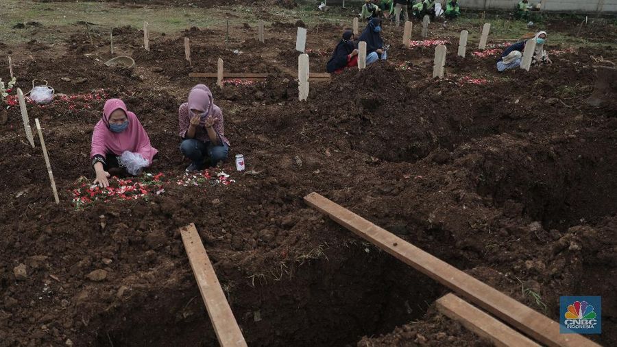 Petugas membawa peti jenazah yang akan dimakamkan dengan protokol COVID-19 di area khusus TPU Srengseng Sawah, Jakarta, Jumat (15/1/2021). TPU Srengseng Sawah mulai menerima pemakaman jenazah dengan protokol COVID-19 sejak Selasa (12/1) lalu. Menurut petugas makam dalam tiga hari terakhir sudah 164 jenazah Covid-19 yang dikubur di TPU tersebut. Lahan pemakaman di Pondok Rangon dan Tegal Alur yang saat ini menjadi lahan pemakaman pasien Corona Virus Desease 2019 (COVID-19) yang hampir penuh. Meski untuk jenazah pasien Covid 19, jenazah non Covid-19 masih bisa digunakan untuk pemakaman. Pantauan CNBC Indonesia sampai pukul 14.00 wib sudah 20 jenazah yang dimakamkan, dan kemungkinan akan bertambah lagi. Ada empat TPU di wilayah Jakarta yang digunakan untuk memakamkan jenazah pasien Covid-19, yakni TPU Tegal Alur di Jakarta Barat, TPU Pondok Ranggon di Jakarta Timur, TPU Rorotan di Jakarta Utara, dan TPU Srengseng Sawah. Dikutip dari CNN Indonesia pada Kamis, 14/1, Kepala Suku Dinas Pertamanan dan Hutan Kota Jakarta Selatan Winarto mengatakan, lahan di TPU Srengseng Sawah digunakan untuk memakamkan jenazah Covid-19 muslim. Dalam menangani krisis lahan pemakaman ini, pihak TPU Pondok Ranggon maupun TPU Tegal Alur juga menerapkan makam tumpang. Namun, mekanisme tersebut harus mendapat izin pihak keluarga. (CNBC Indonesia/ Muhammad Sabki)