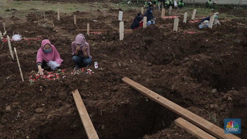 Petugas membawa peti jenazah yang akan dimakamkan dengan protokol COVID-19 di area khusus TPU Srengseng Sawah, Jakarta, Jumat (15/1/2021). TPU Srengseng Sawah mulai menerima pemakaman jenazah dengan protokol COVID-19 sejak Selasa (12/1) lalu. Menurut petugas makam dalam tiga hari terakhir sudah 164 jenazah Covid-19 yang dikubur di TPU tersebut. Lahan pemakaman di Pondok Rangon dan Tegal Alur yang saat ini menjadi lahan pemakaman pasien Corona Virus Desease 2019 (COVID-19) yang hampir penuh. Meski untuk jenazah pasien Covid 19, jenazah non Covid-19 masih bisa digunakan untuk pemakaman. Pantauan CNBC Indonesia sampai pukul 14.00 wib sudah 20 jenazah yang dimakamkan, dan kemungkinan akan bertambah lagi. Ada empat TPU di wilayah Jakarta yang digunakan untuk memakamkan jenazah pasien Covid-19, yakni TPU Tegal Alur di Jakarta Barat, TPU Pondok Ranggon di Jakarta Timur, TPU Rorotan di Jakarta Utara, dan TPU Srengseng Sawah. Dikutip dari CNN Indonesia pada Kamis, 14/1, Kepala Suku Dinas Pertamanan dan Hutan Kota Jakarta Selatan Winarto mengatakan, lahan di TPU Srengseng Sawah digunakan untuk memakamkan jenazah Covid-19 muslim. Dalam menangani krisis lahan pemakaman ini, pihak TPU Pondok Ranggon maupun TPU Tegal Alur juga menerapkan makam tumpang. Namun, mekanisme tersebut harus mendapat izin pihak keluarga. (CNBC Indonesia/ Muhammad Sabki)