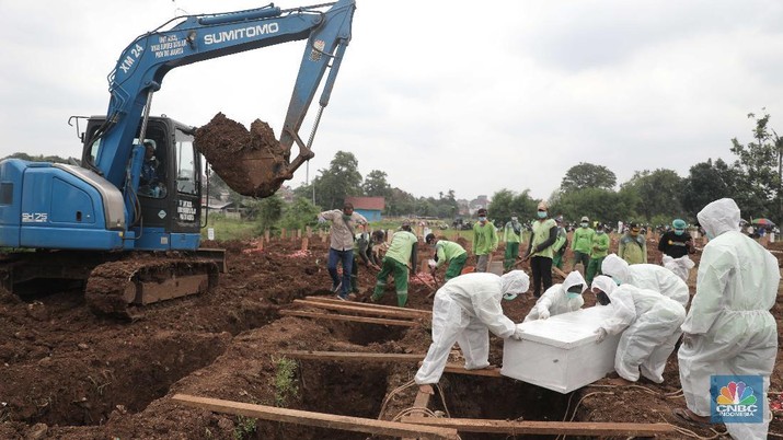 Petugas membawa peti jenazah yang akan dimakamkan dengan protokol COVID-19 di area khusus TPU Srengseng Sawah, Jakarta, Jumat (15/1/2021). TPU Srengseng Sawah mulai menerima pemakaman jenazah dengan protokol COVID-19 sejak Selasa (12/1) lalu. Menurut petugas makam dalam tiga hari terakhir sudah 164 jenazah Covid-19 yang dikubur di TPU tersebut. Lahan pemakaman di Pondok Rangon dan Tegal Alur yang saat ini menjadi lahan pemakaman pasien Corona Virus Desease 2019 (COVID-19) yang hampir penuh. Meski untuk jenazah pasien Covid 19, jenazah non Covid-19 masih bisa digunakan untuk pemakaman. Pantauan CNBC Indonesia sampai pukul 14.00 wib sudah 20 jenazah yang dimakamkan, dan kemungkinan akan bertambah lagi. Ada empat TPU di wilayah Jakarta yang digunakan untuk memakamkan jenazah pasien Covid-19, yakni TPU Tegal Alur di Jakarta Barat, TPU Pondok Ranggon di Jakarta Timur, TPU Rorotan di Jakarta Utara, dan TPU Srengseng Sawah. Dikutip dari CNN Indonesia pada Kamis, 14/1, Kepala Suku Dinas Pertamanan dan Hutan Kota Jakarta Selatan Winarto mengatakan, lahan di TPU Srengseng Sawah digunakan untuk memakamkan jenazah Covid-19 muslim. Dalam menangani krisis lahan pemakaman ini, pihak TPU Pondok Ranggon maupun TPU Tegal Alur juga menerapkan makam tumpang. Namun, mekanisme tersebut harus mendapat izin pihak keluarga. (CNBC Indonesia/ Muhammad Sabki)