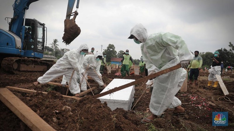 Petugas membawa peti jenazah yang akan dimakamkan dengan protokol COVID-19 di area khusus TPU Srengseng Sawah, Jakarta, Jumat (15/1/2021). TPU Srengseng Sawah mulai menerima pemakaman jenazah dengan protokol COVID-19 sejak Selasa (12/1) lalu. Menurut petugas makam dalam tiga hari terakhir sudah 164 jenazah Covid-19 yang dikubur di TPU tersebut. Lahan pemakaman di Pondok Rangon dan Tegal Alur yang saat ini menjadi lahan pemakaman pasien Corona Virus Desease 2019 (COVID-19) yang hampir penuh. Meski untuk jenazah pasien Covid 19, jenazah non Covid-19 masih bisa digunakan untuk pemakaman. Pantauan CNBC Indonesia sampai pukul 14.00 wib sudah 20 jenazah yang dimakamkan, dan kemungkinan akan bertambah lagi. Ada empat TPU di wilayah Jakarta yang digunakan untuk memakamkan jenazah pasien Covid-19, yakni TPU Tegal Alur di Jakarta Barat, TPU Pondok Ranggon di Jakarta Timur, TPU Rorotan di Jakarta Utara, dan TPU Srengseng Sawah. Dikutip dari CNN Indonesia pada Kamis, 14/1, Kepala Suku Dinas Pertamanan dan Hutan Kota Jakarta Selatan Winarto mengatakan, lahan di TPU Srengseng Sawah digunakan untuk memakamkan jenazah Covid-19 muslim. Dalam menangani krisis lahan pemakaman ini, pihak TPU Pondok Ranggon maupun TPU Tegal Alur juga menerapkan makam tumpang. Namun, mekanisme tersebut harus mendapat izin pihak keluarga. (CNBC Indonesia/ Muhammad Sabki)
