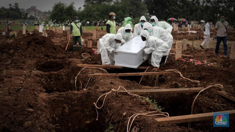 Petugas membawa peti jenazah yang akan dimakamkan dengan protokol COVID-19 di area khusus TPU Srengseng Sawah, Jakarta, Jumat (15/1/2021). TPU Srengseng Sawah mulai menerima pemakaman jenazah dengan protokol COVID-19 sejak Selasa (12/1) lalu. Menurut petugas makam dalam tiga hari terakhir sudah 164 jenazah Covid-19 yang dikubur di TPU tersebut. Lahan pemakaman di Pondok Rangon dan Tegal Alur yang saat ini menjadi lahan pemakaman pasien Corona Virus Desease 2019 (COVID-19) yang hampir penuh. Meski untuk jenazah pasien Covid 19, jenazah non Covid-19 masih bisa digunakan untuk pemakaman. Pantauan CNBC Indonesia sampai pukul 14.00 wib sudah 20 jenazah yang dimakamkan, dan kemungkinan akan bertambah lagi. Ada empat TPU di wilayah Jakarta yang digunakan untuk memakamkan jenazah pasien Covid-19, yakni TPU Tegal Alur di Jakarta Barat, TPU Pondok Ranggon di Jakarta Timur, TPU Rorotan di Jakarta Utara, dan TPU Srengseng Sawah. Dikutip dari CNN Indonesia pada Kamis, 14/1, Kepala Suku Dinas Pertamanan dan Hutan Kota Jakarta Selatan Winarto mengatakan, lahan di TPU Srengseng Sawah digunakan untuk memakamkan jenazah Covid-19 muslim. Dalam menangani krisis lahan pemakaman ini, pihak TPU Pondok Ranggon maupun TPU Tegal Alur juga menerapkan makam tumpang. Namun, mekanisme tersebut harus mendapat izin pihak keluarga. (CNBC Indonesia/ Muhammad Sabki)