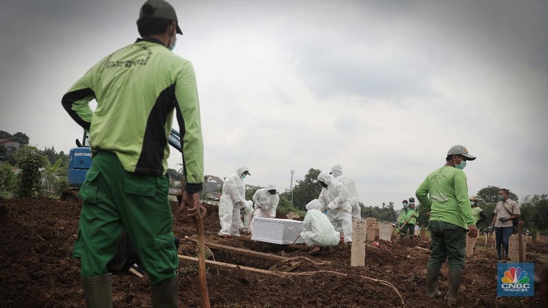 Petugas membawa peti jenazah yang akan dimakamkan dengan protokol COVID-19 di area khusus TPU Srengseng Sawah, Jakarta, Jumat (15/1/2021). TPU Srengseng Sawah mulai menerima pemakaman jenazah dengan protokol COVID-19 sejak Selasa (12/1) lalu. Menurut petugas makam dalam tiga hari terakhir sudah 164 jenazah Covid-19 yang dikubur di TPU tersebut. Lahan pemakaman di Pondok Rangon dan Tegal Alur yang saat ini menjadi lahan pemakaman pasien Corona Virus Desease 2019 (COVID-19) yang hampir penuh. Meski untuk jenazah pasien Covid 19, jenazah non Covid-19 masih bisa digunakan untuk pemakaman. Pantauan CNBC Indonesia sampai pukul 14.00 wib sudah 20 jenazah yang dimakamkan, dan kemungkinan akan bertambah lagi. Ada empat TPU di wilayah Jakarta yang digunakan untuk memakamkan jenazah pasien Covid-19, yakni TPU Tegal Alur di Jakarta Barat, TPU Pondok Ranggon di Jakarta Timur, TPU Rorotan di Jakarta Utara, dan TPU Srengseng Sawah. Dikutip dari CNN Indonesia pada Kamis, 14/1, Kepala Suku Dinas Pertamanan dan Hutan Kota Jakarta Selatan Winarto mengatakan, lahan di TPU Srengseng Sawah digunakan untuk memakamkan jenazah Covid-19 muslim. Dalam menangani krisis lahan pemakaman ini, pihak TPU Pondok Ranggon maupun TPU Tegal Alur juga menerapkan makam tumpang. Namun, mekanisme tersebut harus mendapat izin pihak keluarga. (CNBC Indonesia/ Muhammad Sabki)