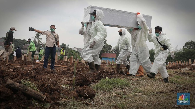 Petugas membawa peti jenazah yang akan dimakamkan dengan protokol COVID-19 di area khusus TPU Srengseng Sawah, Jakarta, Jumat (15/1/2021). TPU Srengseng Sawah mulai menerima pemakaman jenazah dengan protokol COVID-19 sejak Selasa (12/1) lalu. Menurut petugas makam dalam tiga hari terakhir sudah 164 jenazah Covid-19 yang dikubur di TPU tersebut. Lahan pemakaman di Pondok Rangon dan Tegal Alur yang saat ini menjadi lahan pemakaman pasien Corona Virus Desease 2019 (COVID-19) yang hampir penuh. Meski untuk jenazah pasien Covid 19, jenazah non Covid-19 masih bisa digunakan untuk pemakaman. Pantauan CNBC Indonesia sampai pukul 14.00 wib sudah 20 jenazah yang dimakamkan, dan kemungkinan akan bertambah lagi. Ada empat TPU di wilayah Jakarta yang digunakan untuk memakamkan jenazah pasien Covid-19, yakni TPU Tegal Alur di Jakarta Barat, TPU Pondok Ranggon di Jakarta Timur, TPU Rorotan di Jakarta Utara, dan TPU Srengseng Sawah. Dikutip dari CNN Indonesia pada Kamis, 14/1, Kepala Suku Dinas Pertamanan dan Hutan Kota Jakarta Selatan Winarto mengatakan, lahan di TPU Srengseng Sawah digunakan untuk memakamkan jenazah Covid-19 muslim. Dalam menangani krisis lahan pemakaman ini, pihak TPU Pondok Ranggon maupun TPU Tegal Alur juga menerapkan makam tumpang. Namun, mekanisme tersebut harus mendapat izin pihak keluarga. (CNBC Indonesia/ Muhammad Sabki)