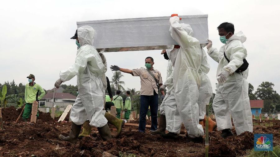 Petugas membawa peti jenazah yang akan dimakamkan dengan protokol COVID-19 di area khusus TPU Srengseng Sawah, Jakarta, Jumat (15/1/2021). TPU Srengseng Sawah mulai menerima pemakaman jenazah dengan protokol COVID-19 sejak Selasa (12/1) lalu. Menurut petugas makam dalam tiga hari terakhir sudah 164 jenazah Covid-19 yang dikubur di TPU tersebut. Lahan pemakaman di Pondok Rangon dan Tegal Alur yang saat ini menjadi lahan pemakaman pasien Corona Virus Desease 2019 (COVID-19) yang hampir penuh. Meski untuk jenazah pasien Covid 19, jenazah non Covid-19 masih bisa digunakan untuk pemakaman. Pantauan CNBC Indonesia sampai pukul 14.00 wib sudah 20 jenazah yang dimakamkan, dan kemungkinan akan bertambah lagi. Ada empat TPU di wilayah Jakarta yang digunakan untuk memakamkan jenazah pasien Covid-19, yakni TPU Tegal Alur di Jakarta Barat, TPU Pondok Ranggon di Jakarta Timur, TPU Rorotan di Jakarta Utara, dan TPU Srengseng Sawah. Dikutip dari CNN Indonesia pada Kamis, 14/1, Kepala Suku Dinas Pertamanan dan Hutan Kota Jakarta Selatan Winarto mengatakan, lahan di TPU Srengseng Sawah digunakan untuk memakamkan jenazah Covid-19 muslim. Dalam menangani krisis lahan pemakaman ini, pihak TPU Pondok Ranggon maupun TPU Tegal Alur juga menerapkan makam tumpang. Namun, mekanisme tersebut harus mendapat izin pihak keluarga. (CNBC Indonesia/ Muhammad Sabki)