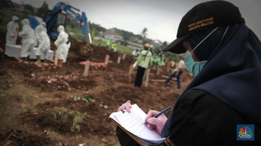 Petugas membawa peti jenazah yang akan dimakamkan dengan protokol COVID-19 di area khusus TPU Srengseng Sawah, Jakarta, Jumat (15/1/2021). TPU Srengseng Sawah mulai menerima pemakaman jenazah dengan protokol COVID-19 sejak Selasa (12/1) lalu. Menurut petugas makam dalam tiga hari terakhir sudah 164 jenazah Covid-19 yang dikubur di TPU tersebut. Lahan pemakaman di Pondok Rangon dan Tegal Alur yang saat ini menjadi lahan pemakaman pasien Corona Virus Desease 2019 (COVID-19) yang hampir penuh. Meski untuk jenazah pasien Covid 19, jenazah non Covid-19 masih bisa digunakan untuk pemakaman. Pantauan CNBC Indonesia sampai pukul 14.00 wib sudah 20 jenazah yang dimakamkan, dan kemungkinan akan bertambah lagi. Ada empat TPU di wilayah Jakarta yang digunakan untuk memakamkan jenazah pasien Covid-19, yakni TPU Tegal Alur di Jakarta Barat, TPU Pondok Ranggon di Jakarta Timur, TPU Rorotan di Jakarta Utara, dan TPU Srengseng Sawah. Dikutip dari CNN Indonesia pada Kamis, 14/1, Kepala Suku Dinas Pertamanan dan Hutan Kota Jakarta Selatan Winarto mengatakan, lahan di TPU Srengseng Sawah digunakan untuk memakamkan jenazah Covid-19 muslim. Dalam menangani krisis lahan pemakaman ini, pihak TPU Pondok Ranggon maupun TPU Tegal Alur juga menerapkan makam tumpang. Namun, mekanisme tersebut harus mendapat izin pihak keluarga. (CNBC Indonesia/ Muhammad Sabki)