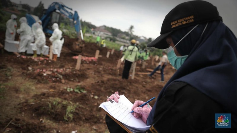 Petugas membawa peti jenazah yang akan dimakamkan dengan protokol COVID-19 di area khusus TPU Srengseng Sawah, Jakarta, Jumat (15/1/2021). TPU Srengseng Sawah mulai menerima pemakaman jenazah dengan protokol COVID-19 sejak Selasa (12/1) lalu. Menurut petugas makam dalam tiga hari terakhir sudah 164 jenazah Covid-19 yang dikubur di TPU tersebut. Lahan pemakaman di Pondok Rangon dan Tegal Alur yang saat ini menjadi lahan pemakaman pasien Corona Virus Desease 2019 (COVID-19) yang hampir penuh. Meski untuk jenazah pasien Covid 19, jenazah non Covid-19 masih bisa digunakan untuk pemakaman. Pantauan CNBC Indonesia sampai pukul 14.00 wib sudah 20 jenazah yang dimakamkan, dan kemungkinan akan bertambah lagi. Ada empat TPU di wilayah Jakarta yang digunakan untuk memakamkan jenazah pasien Covid-19, yakni TPU Tegal Alur di Jakarta Barat, TPU Pondok Ranggon di Jakarta Timur, TPU Rorotan di Jakarta Utara, dan TPU Srengseng Sawah. Dikutip dari CNN Indonesia pada Kamis, 14/1, Kepala Suku Dinas Pertamanan dan Hutan Kota Jakarta Selatan Winarto mengatakan, lahan di TPU Srengseng Sawah digunakan untuk memakamkan jenazah Covid-19 muslim. Dalam menangani krisis lahan pemakaman ini, pihak TPU Pondok Ranggon maupun TPU Tegal Alur juga menerapkan makam tumpang. Namun, mekanisme tersebut harus mendapat izin pihak keluarga. (CNBC Indonesia/ Muhammad Sabki)