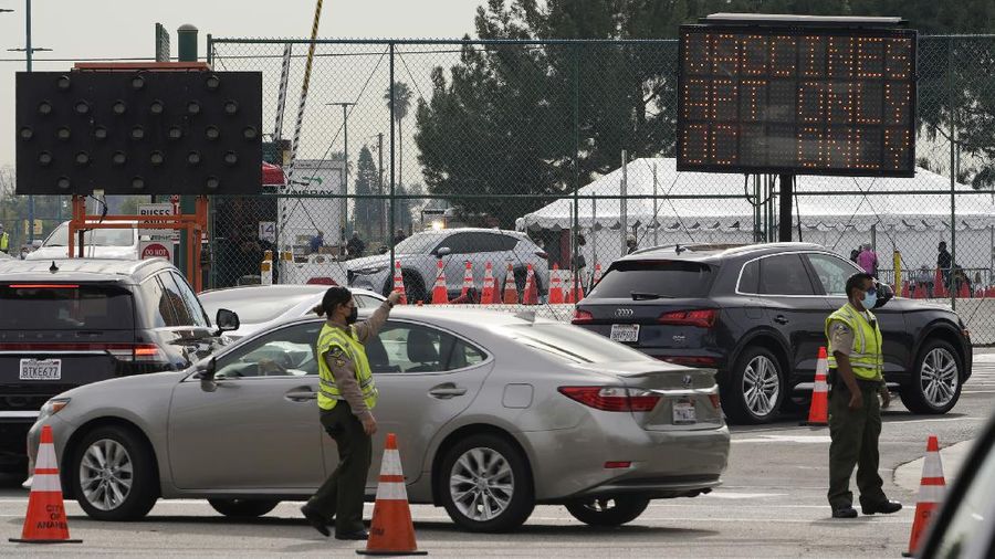People walk after receiving their vaccines at the Disneyland Resort, serving as a Super POD (Point of Dispensing) COVID-19 mass vaccination site in Anaheim, Calif., Wednesday, Jan. 13, 2021. The parking lot is located off Katella Avenue and sits southeast of Disneyland. California is immediately allowing residents 65 and older to get scarce coronavirus vaccines, Gov. Gavin Newsom announced Wednesday. (AP Photo/Damian Dovarganes)