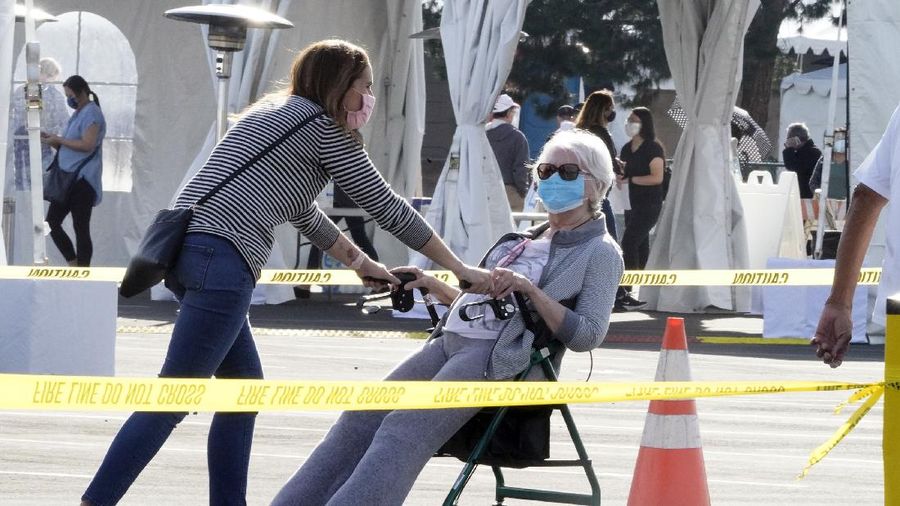 People walk after receiving their vaccines at the Disneyland Resort, serving as a Super POD (Point of Dispensing) COVID-19 mass vaccination site in Anaheim, Calif., Wednesday, Jan. 13, 2021. The parking lot is located off Katella Avenue and sits southeast of Disneyland. California is immediately allowing residents 65 and older to get scarce coronavirus vaccines, Gov. Gavin Newsom announced Wednesday. (AP Photo/Damian Dovarganes)