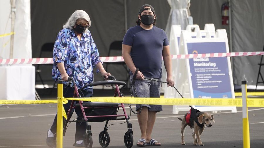 People walk after receiving their vaccines at the Disneyland Resort, serving as a Super POD (Point of Dispensing) COVID-19 mass vaccination site in Anaheim, Calif., Wednesday, Jan. 13, 2021. The parking lot is located off Katella Avenue and sits southeast of Disneyland. California is immediately allowing residents 65 and older to get scarce coronavirus vaccines, Gov. Gavin Newsom announced Wednesday. (AP Photo/Damian Dovarganes)