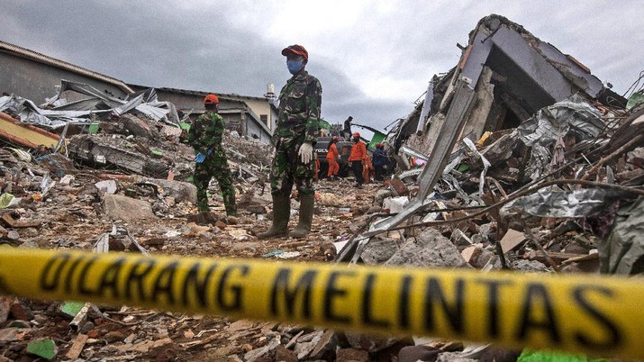 Rescuers search for victims at the ruin of a building flattened during an earthquake in Mamuju, West Sulawesi, Indonesia, Saturday, Jan. 16, 2021. Damaged roads and bridges, power blackouts and lack of heavy equipment on Saturday hampered Indonesia's rescuers after a strong and shallow earthquake left a number of people dead and injured on Sulawesi island. (AP Photo/Yusuf Wahil)