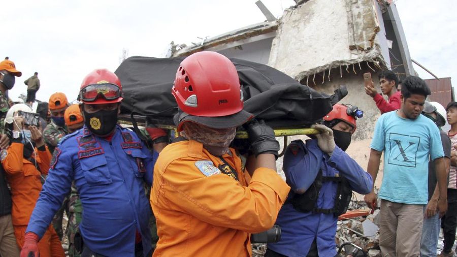 Rescuers carry the body of an earthquake victim retrieved from the ruin of a building damaged by an earthquake in Mamuju, West Sulawesi, Indonesia, Saturday, Jan. 16, 2021. Damaged roads and bridges, power blackouts and lack of heavy equipment on Saturday hampered Indonesia's rescuers after a strong and shallow earthquake left a number of people dead and injured on Sulawesi island. (AP Photo/Bamu Saseno)