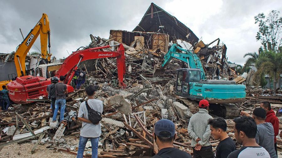 Rescuers assist a survivor pulled out from the ruin of a government building collapsed during an earthquake in Mamuju, West Sulawesi, Indonesia, Friday, Jan. 15, 2021. A strong, shallow earthquake shook Indonesia's Sulawesi island just after midnight Friday, toppling homes and buildings, triggering landslides and killing a number of people. (AP Photo/Azhari Surahman)
