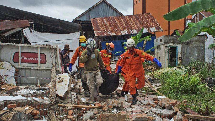 Rescuers assist a survivor pulled out from the ruin of a government building collapsed during an earthquake in Mamuju, West Sulawesi, Indonesia, Friday, Jan. 15, 2021. A strong, shallow earthquake shook Indonesia's Sulawesi island just after midnight Friday, toppling homes and buildings, triggering landslides and killing a number of people. (AP Photo/Azhari Surahman)