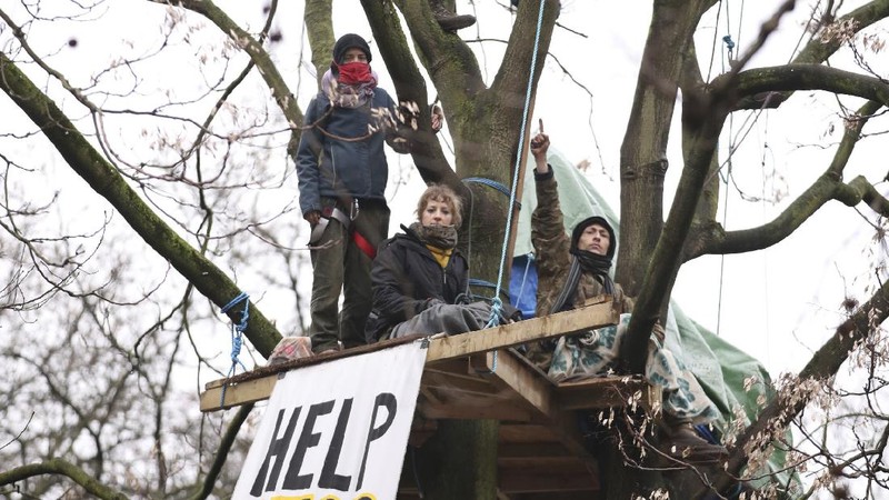 Para pengunjuk rasa duduk di atas pepohonan di perkemahan di Euston Square Gardens di pusat kota London, Inggris, Rabu (27/1/2021). (AP/Aaron Chown)