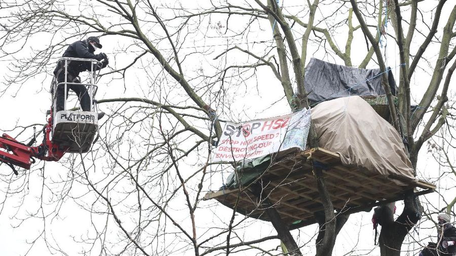 Para pengunjuk rasa duduk di atas pepohonan di perkemahan di Euston Square Gardens di pusat kota London, Inggris, Rabu (27/1/2021). (AP/Aaron Chown)