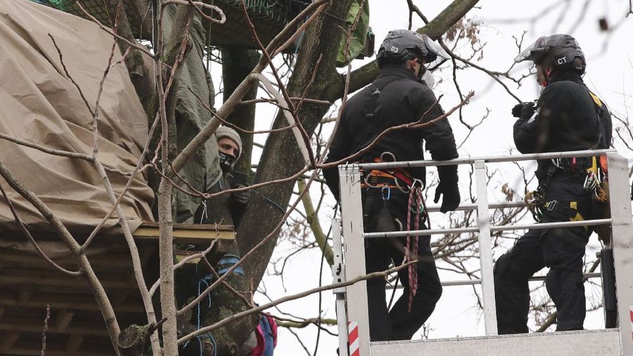 Para pengunjuk rasa duduk di atas pepohonan di perkemahan di Euston Square Gardens di pusat kota London, Inggris, Rabu (27/1/2021). (AP/Aaron Chown)