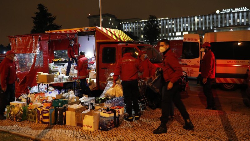 Petugas medis berdiri di samping ambulans saat mereka menunggu di rumah sakit Santa Maria, Lisbon, Portugal. (AP/Armando Franca)