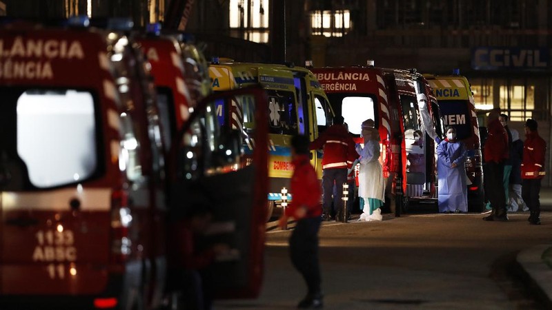 Petugas medis berdiri di samping ambulans saat mereka menunggu di rumah sakit Santa Maria, Lisbon, Portugal. (AP/Armando Franca)