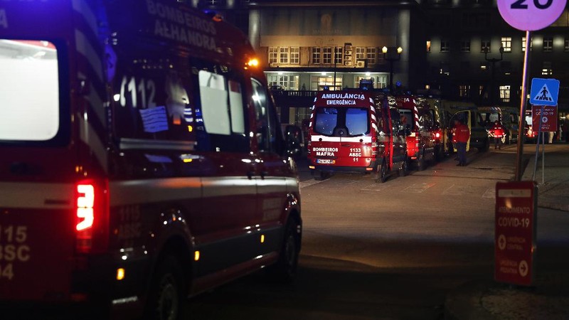 Petugas medis berdiri di samping ambulans saat mereka menunggu di rumah sakit Santa Maria, Lisbon, Portugal. (AP/Armando Franca)