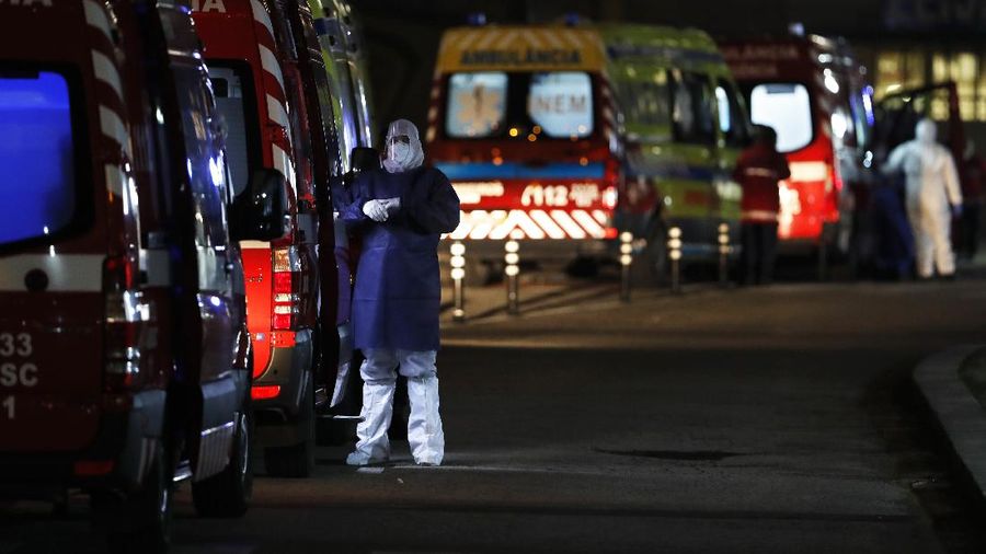 Petugas medis berdiri di samping ambulans saat mereka menunggu di rumah sakit Santa Maria, Lisbon, Portugal. (AP/Armando Franca)