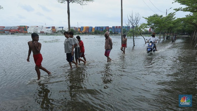 Warga melewati genangan air di pemakaman TPU Semper yang terendam banjir di Jakarta Utara, Rabu (3/2/2021). Banjir tersebut terjadi akibat tidak adanya saluran pembuangan air yang menyebabkan terendamnya ratusan makam. TPU Semper mengalami banjir sejak sekitar tahun 2000an akibat intensitas curah hujan yang tinggi. TPU Semper berada di atas lahan seluas sekitar 72 hektare dengan total 108.709 makam sejak dibuka pada 1984. Di bagian Selatan TPU adalah terminal peti kemas yang memanjang mengikuti luas area  (CNBC Indonesia/ Tri Susilo)