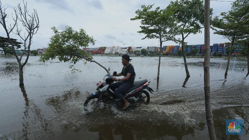 Warga melewati genangan air di pemakaman TPU Semper yang terendam banjir di Jakarta Utara, Rabu (3/2/2021). Banjir tersebut terjadi akibat tidak adanya saluran pembuangan air yang menyebabkan terendamnya ratusan makam. TPU Semper mengalami banjir sejak sekitar tahun 2000an akibat intensitas curah hujan yang tinggi. TPU Semper berada di atas lahan seluas sekitar 72 hektare dengan total 108.709 makam sejak dibuka pada 1984. Di bagian Selatan TPU adalah terminal peti kemas yang memanjang mengikuti luas area  (CNBC Indonesia/ Tri Susilo)