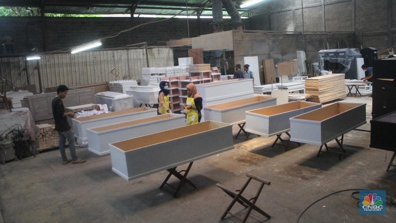 Pekerja menyelesaikan pembuatan peti khusus jenazah COVID-19 di Funisia Perkasa, Kota Tangerang, Banten, Rabu (3/2/2021). Pabrik furnitur tersebut kini memproduksi peti untuk jenazah COVID-19 dan bisa menghasilkan 50 hingga 100 buah peti per harinya. Lonjakan kasus Covid-19 berdampak pada permintaan peti mati. (CNBC Indonesia/ Muhammad Sabki)