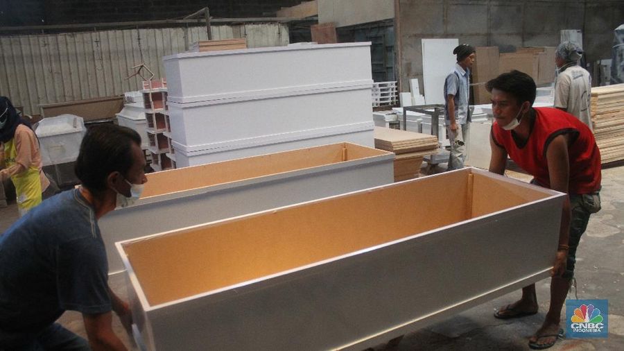 Pekerja menyelesaikan pembuatan peti khusus jenazah COVID-19 di Funisia Perkasa, Kota Tangerang, Banten, Rabu (3/2/2021). Pabrik furnitur tersebut kini memproduksi peti untuk jenazah COVID-19 dan bisa menghasilkan 50 hingga 100 buah peti per harinya. Lonjakan kasus Covid-19 berdampak pada permintaan peti mati. (CNBC Indonesia/ Muhammad Sabki)