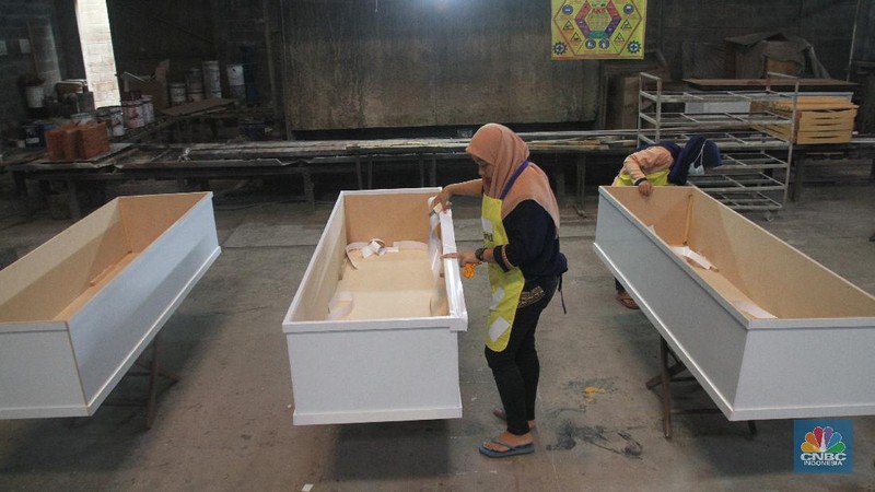 Pekerja menyelesaikan pembuatan peti khusus jenazah COVID-19 di Funisia Perkasa, Kota Tangerang, Banten, Rabu (3/2/2021). Pabrik furnitur tersebut kini memproduksi peti untuk jenazah COVID-19 dan bisa menghasilkan 50 hingga 100 buah peti per harinya. Lonjakan kasus Covid-19 berdampak pada permintaan peti mati. (CNBC Indonesia/ Muhammad Sabki)