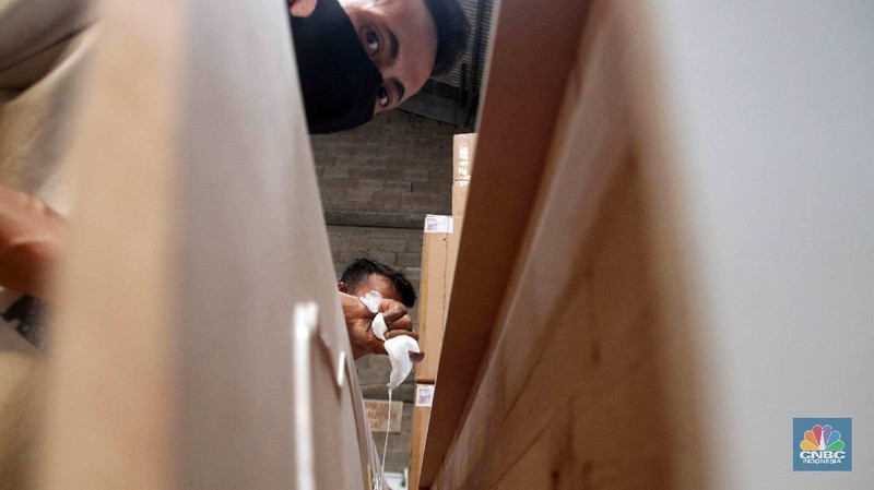 Pekerja menyelesaikan pembuatan peti khusus jenazah COVID-19 di Funisia Perkasa, Kota Tangerang, Banten, Rabu (3/2/2021). Pabrik furnitur tersebut kini memproduksi peti untuk jenazah COVID-19 dan bisa menghasilkan 50 hingga 100 buah peti per harinya. Lonjakan kasus Covid-19 berdampak pada permintaan peti mati. (CNBC Indonesia/ Muhammad Sabki)