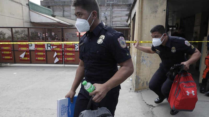 Rescuers stand inside the compound of the TP Marcelo Ice Plant Thursday, Feb. 4, 2021 in Navotas, Philippines. An ammonia leak from the ice plant in the Philippine capital region left some dead and more than 90 other injured or sickened while hundreds of residents fled to safety, an official said. The plant was ordered closed shortly after the leak. (AP Photo/Aaron Favila)