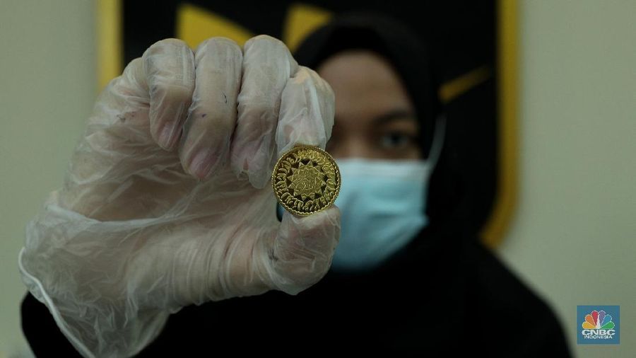 Petugas menunjukkan koin emas Dirham di Gerai Butik Emas Antam, Jakarta, Kamis (4/2/2021). Bank Indonesia (BI) mengajak masyarakat dan berbagai pihak untuk menjaga kedaulatan Rupiah sebagai mata uang NKRI.    (CNBC Indonesia/ Tri Susislo)