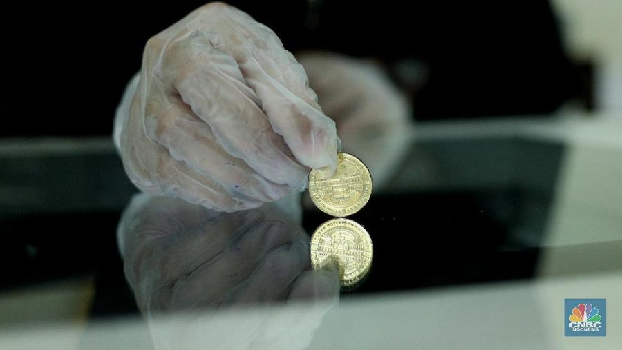 Petugas menunjukkan koin emas Dirham di Gerai Butik Emas Antam, Jakarta, Kamis (4/2/2021). Bank Indonesia (BI) mengajak masyarakat dan berbagai pihak untuk menjaga kedaulatan Rupiah sebagai mata uang NKRI.    (CNBC Indonesia/ Tri Susislo)