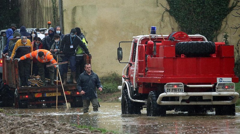 A rescue worker, left, and volunteers help residents in a flooded street of Le Gond-Pontouvre, near Angouleme, southwestern France, Friday, Feb 5, 2021. In southern France, waters are starting to recede after the worst flooding in 40 years swelled the Garonne River between Bordeaux and Toulouse. (AP Photo/Yohan Bonnet)