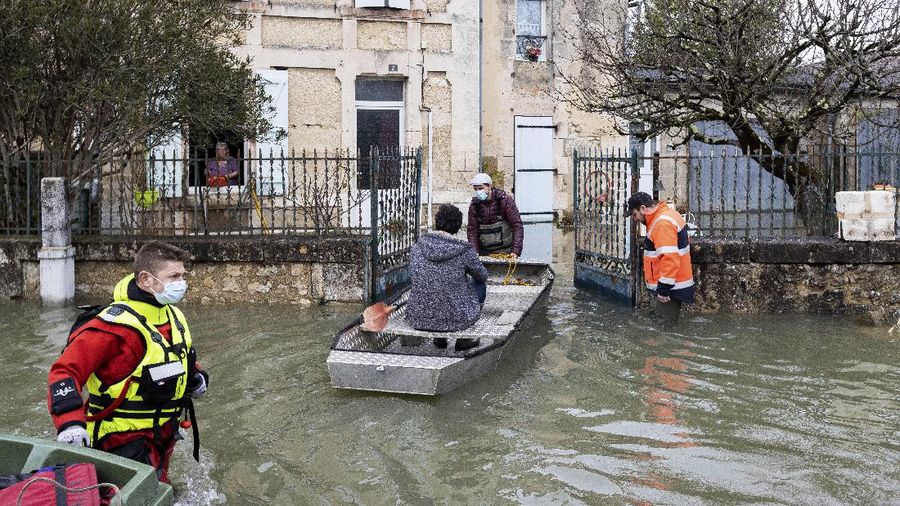 A rescue worker, left, and volunteers help residents in a flooded street of Le Gond-Pontouvre, near Angouleme, southwestern France, Friday, Feb 5, 2021. In southern France, waters are starting to recede after the worst flooding in 40 years swelled the Garonne River between Bordeaux and Toulouse. (AP Photo/Yohan Bonnet)