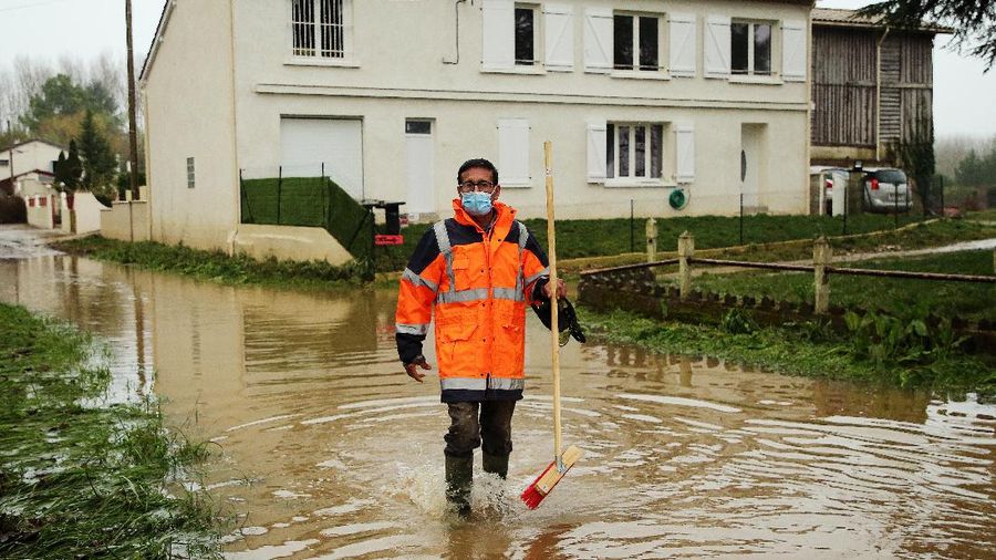 A rescue worker, left, and volunteers help residents in a flooded street of Le Gond-Pontouvre, near Angouleme, southwestern France, Friday, Feb 5, 2021. In southern France, waters are starting to recede after the worst flooding in 40 years swelled the Garonne River between Bordeaux and Toulouse. (AP Photo/Yohan Bonnet)