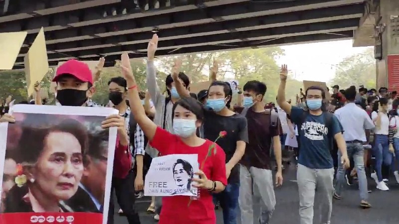 In this image made from video provided by the Democratic Voice of Burma (DVB), protesters hold an image of deposed Myanmar leader Aung San Suu Kyi and former President Win Myint outside the Hladen Center in Yangon, Myanmar Sunday, Feb. 7, 2021.  About 2,000 protesters rallied against the military takeover in Myanmar's biggest city on Sunday and demanded the release of Aung San Suu Kyi, whose elected government was toppled by the army that also imposed an internet blackout.  (DVB via AP)