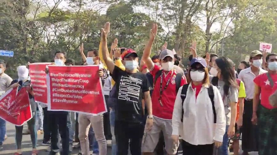 In this image made from video provided by the Democratic Voice of Burma (DVB), protesters hold an image of deposed Myanmar leader Aung San Suu Kyi and former President Win Myint outside the Hladen Center in Yangon, Myanmar Sunday, Feb. 7, 2021.  About 2,000 protesters rallied against the military takeover in Myanmar's biggest city on Sunday and demanded the release of Aung San Suu Kyi, whose elected government was toppled by the army that also imposed an internet blackout.  (DVB via AP)