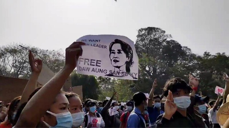 In this image made from video provided by the Democratic Voice of Burma (DVB), protesters hold an image of deposed Myanmar leader Aung San Suu Kyi and former President Win Myint outside the Hladen Center in Yangon, Myanmar Sunday, Feb. 7, 2021.  About 2,000 protesters rallied against the military takeover in Myanmar's biggest city on Sunday and demanded the release of Aung San Suu Kyi, whose elected government was toppled by the army that also imposed an internet blackout.  (DVB via AP)