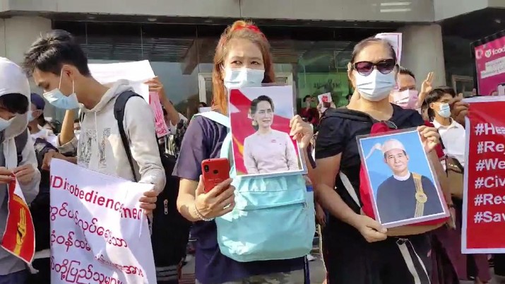 In this image made from video provided by the Democratic Voice of Burma (DVB), protesters hold an image of deposed Myanmar leader Aung San Suu Kyi and former President Win Myint outside the Hladen Center in Yangon, Myanmar Sunday, Feb. 7, 2021.  About 2,000 protesters rallied against the military takeover in Myanmar's biggest city on Sunday and demanded the release of Aung San Suu Kyi, whose elected government was toppled by the army that also imposed an internet blackout.  (DVB via AP)