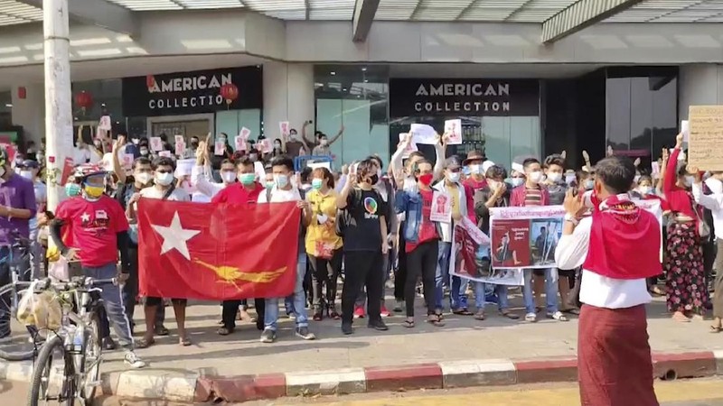In this image made from video provided by the Democratic Voice of Burma (DVB), protesters hold an image of deposed Myanmar leader Aung San Suu Kyi and former President Win Myint outside the Hladen Center in Yangon, Myanmar Sunday, Feb. 7, 2021.  About 2,000 protesters rallied against the military takeover in Myanmar's biggest city on Sunday and demanded the release of Aung San Suu Kyi, whose elected government was toppled by the army that also imposed an internet blackout.  (DVB via AP)