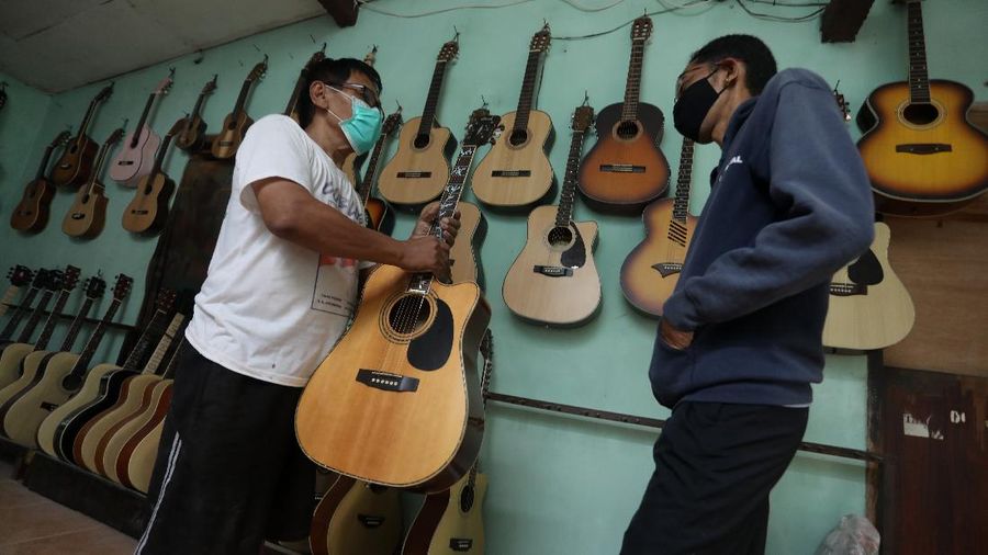 Pengrajjn memperbaiki gitar pelanggan di servis gitar pak Manto, Jakarta Selatan, Senin (8/2/2021). Selain mereparasi gitar, Manto juga memproduksi gitar akustik yang dijual dari harga ratusan ribu hingga juta, tergantung jenis dan tingkat kesulitannya. (CNBC Indonesia/Andrean Kristianto)