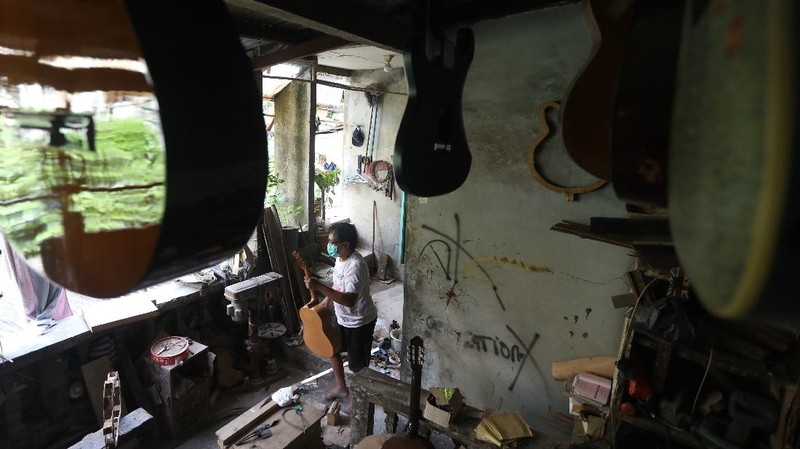 Pengrajjn  memperbaiki gitar pelanggan di servis gitar pak Manto, Jakarta Selatan, Senin (8/2/2021). Selain mereparasi gitar, Manto juga memproduksi gitar akustik yang dijual dari harga ratusan ribu hingga juta, tergantung jenis dan tingkat kesulitannya. (CNBC Indonesia/Andrean Kristianto)